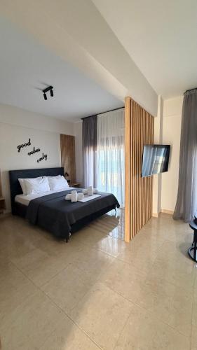 a bedroom with a bed and a flat screen tv at Sabbia Suites in Nea Vrasna
