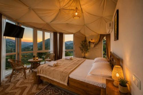 a bedroom with a large bed in a room with windows at Akho Panorama in Batumi