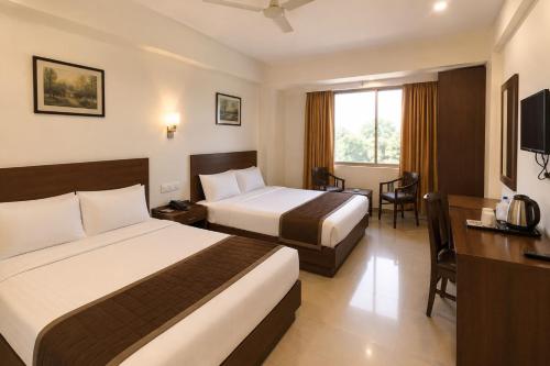 ein Hotelzimmer mit zwei Betten und einem Schreibtisch in der Unterkunft Red Queen in Raigarh