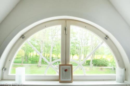 an arched window in a white room with a candle at Södra Lund B&B in Vreta Kloster