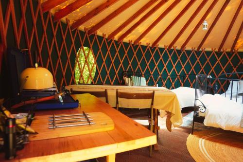 a room with a table and a bed in a tent at Yurtcamp Devon in Heathfield