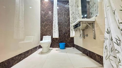 a bathroom with a toilet and a blue trash can at Pildacil in Garut