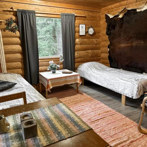 a room with two beds and a table in a log cabin at Seiväslahti in Keuruu