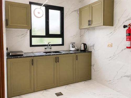a kitchen with green cabinets and a window at Bin Fhaid Suites in Salalah