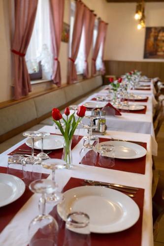 a long table with white plates and red roses on it at ESER Hotel Restaurant in Bad Bellingen