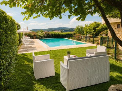 a backyard with a pool and two white chairs at Villa Vale in Casole dʼElsa
