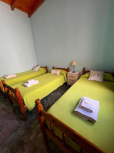 three beds in a room with green sheets at Altos del Pissis I in Tinogasta