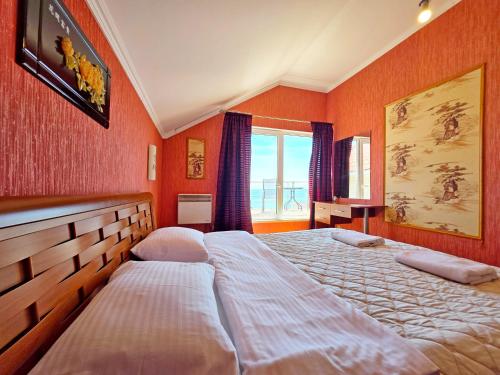 two beds in a bedroom with orange walls at Великі котеджі з терасами у моря Совіньйон in Odesa