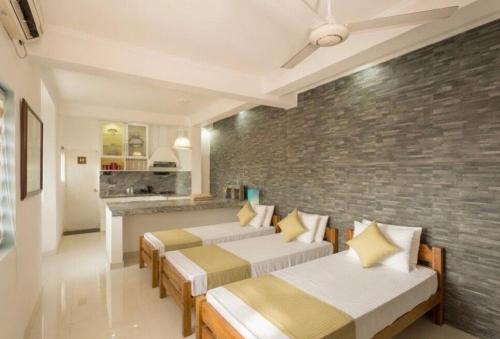a room with three beds and a brick wall at Shalom Residence Kandy in Kandy