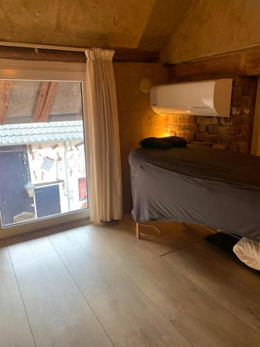a bedroom with a bed and a large window at Althuizenhof - Leem in Doenrade