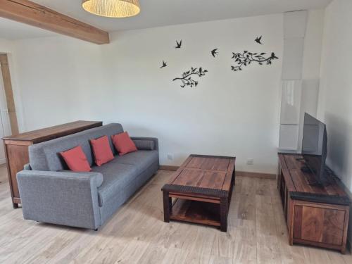 a living room with a couch and a table and a tv at Chez steph studio in Saint-Germain-Nuelles