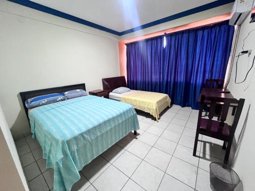 a bedroom with two beds and a window with blue curtains at Alojamiento 22 dé octubre in Santa Cruz de la Sierra