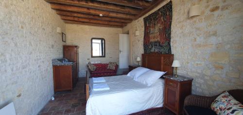 a bedroom with a bed in a stone wall at Les Fleurs de La Brise in Nueil-sous-Faye