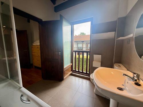 a bathroom with a sink and a toilet and a window at La casa de Nino in Cabanzón