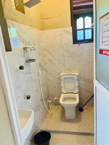 a small bathroom with a toilet and a sink at Akkaraipattu Guest House in Akkaraipattu