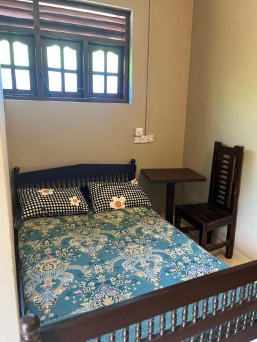 a bedroom with a bed and a chair and a window at Akkaraipattu Guest House in Akkaraipattu
