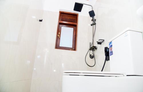 a shower in a white bathroom with a window at Zenora Villa ella in Ella