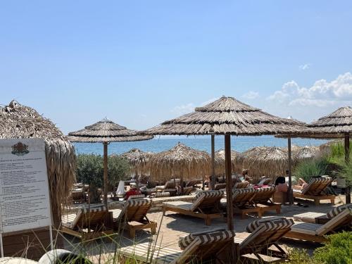 a beach with chairs and straw umbrellas and the ocean at Balchik Sea View Studio in Balchik