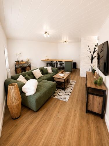 a living room with a green couch and a table at Résidence de la Place in Pont-du-Château
