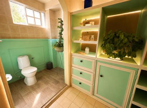 a bathroom with a toilet and green cabinets at Casa Elixir Boutique in Barranquilla