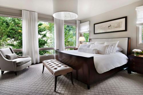 a bedroom with a large bed and a chair and windows at Charlie Hotel in Kakani