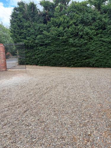 a gravel driveway with a gate and a hedge at River Garden View in Beccles