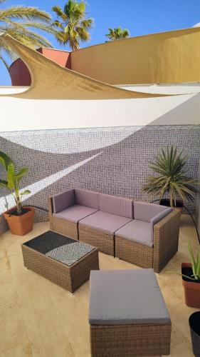 a patio with a couch and tables and plants at Casa Girasoles terraza patio aire acondicionado in Corralejo