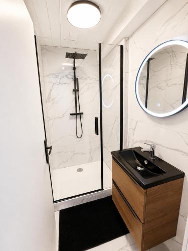 a bathroom with a shower with a sink and a mirror at Résidence de la Place in Pont-du-Château