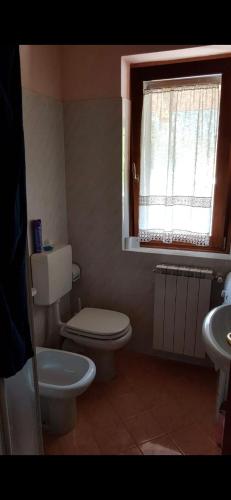 ein Badezimmer mit Toilette, Waschbecken und Fenster in der Unterkunft Chalet Laghetti in Schilpario