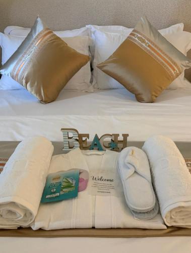 a bed with white towels and pillows on it at Inter Home Coral - beach access in Ras al Khaimah