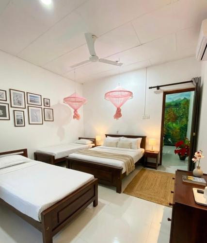 two beds in a room with pink lamps at Hotel Kandy Village Inn in Kandy
