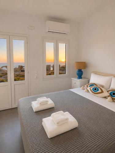 a white bedroom with two towels on a bed at Orama Suite II Mykonos Sunset & Pool in Mikonos