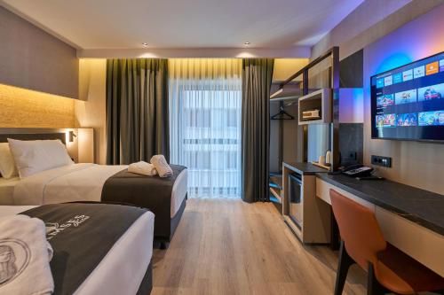 a hotel room with two beds and a flat screen tv at Ramses Hotel İzmir in İzmir