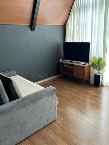 a living room with a couch and a television at Chalé Aconchego in Caparaó Velho