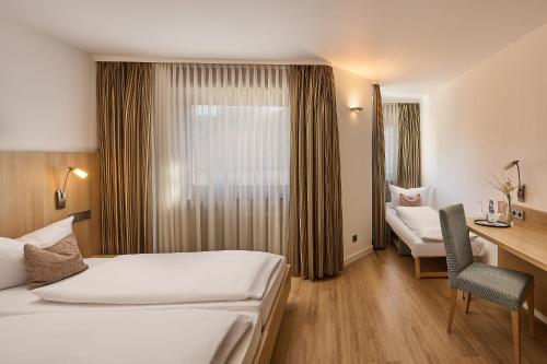 a hotel room with two beds and a desk at City Partner Hotel Berliner Hof in Karlsruhe