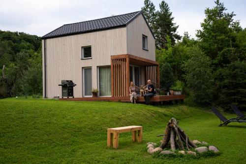 two people sitting on the deck of a house at PrzyStań w Ciszy in Kozielec