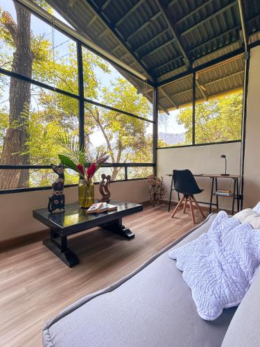 a bedroom with a bed and a table and windows at Minca Ecohabs Hotel in Minca
