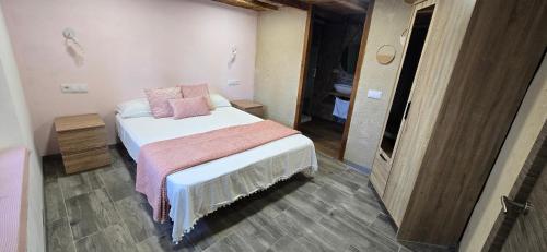 a small bedroom with a bed with pink pillows at El rincon de Fausto in Mudrián
