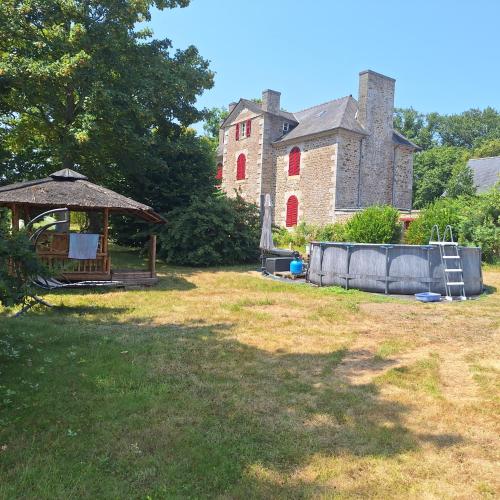 a yard with an old building and a gazebo at Les Roches Blanches Emplacements camping-car, tente, caravane in Guenroc
