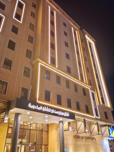 a tall building with a sign in front of it at Sendan Residence in Dammam