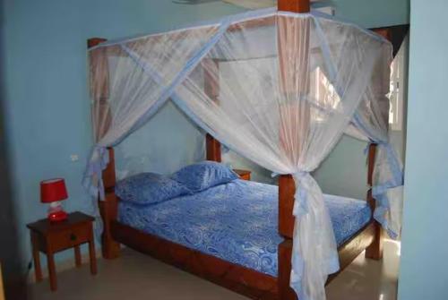 a bedroom with a canopy bed with a blue comforter at Villa Reine Saly in Saly Portudal