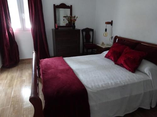 a bedroom with a bed with red pillows on it at Casa do Pinheiro in Louriceira