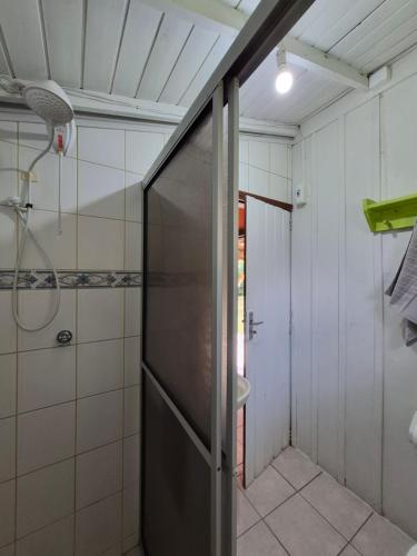 a bathroom with a shower and a glass door at Cabanas Areias in Praia do Rosa