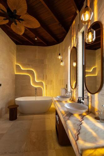 a bathroom with two sinks and a bath tub at Vanara Resort and Spa in Uluwatu