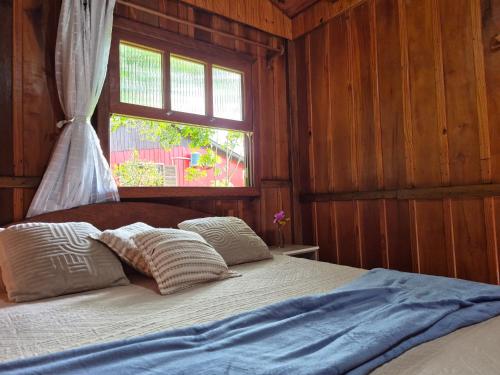 a bed with two pillows in a room with a window at Cabanas Areias in Praia do Rosa