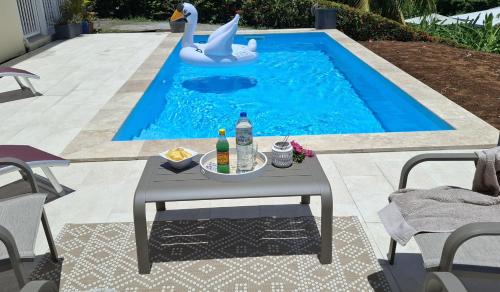 a pool with a table with drinks and a swan float at Le Voyageur in Sainte-Marie