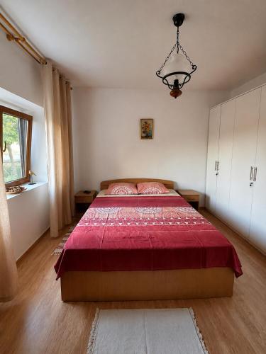 a bedroom with a large bed with a red blanket at Casa de Vacanta Sarinasuf in Sarinasuf