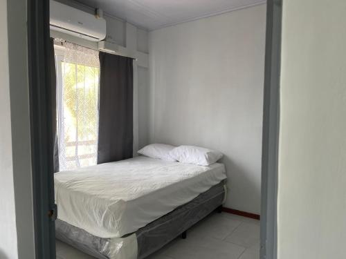 a small bedroom with a bed and a window at Monarca Village in La Libertad