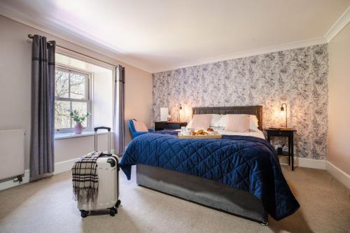 a bedroom with a bed and a suitcase at Redesdale Arms in Otterburn