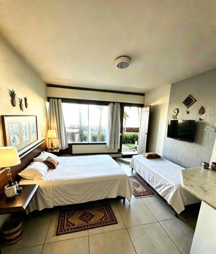 a bedroom with two beds and a large window at Beachfront suite right on the sand in Cabo Frio